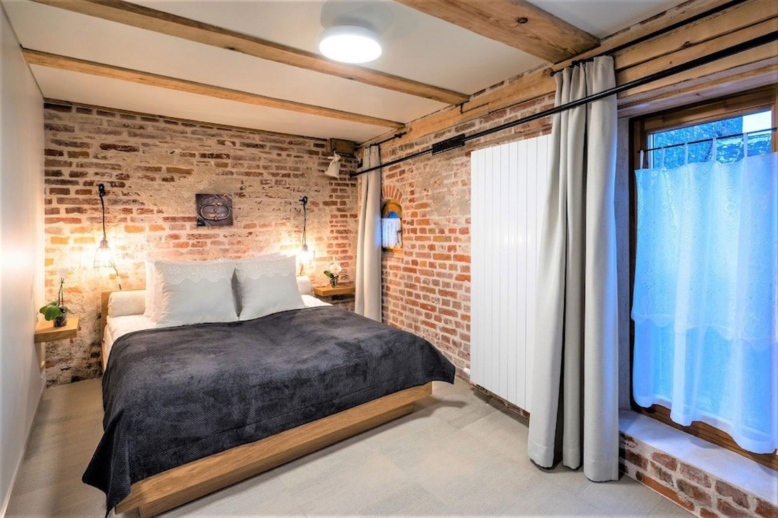 ett sovrum med en tegelvägg, en säng, ett fönster och en radiator