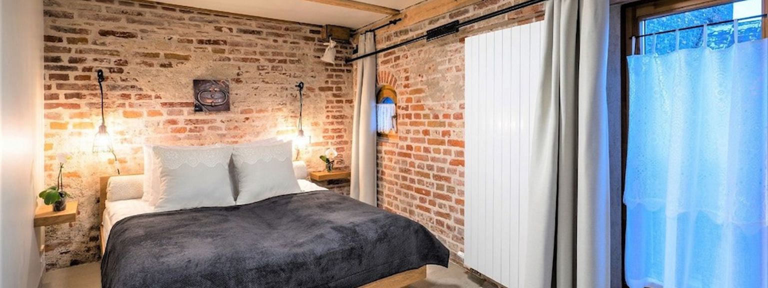 ett sovrum med en tegelvägg, en säng, ett fönster och en radiator