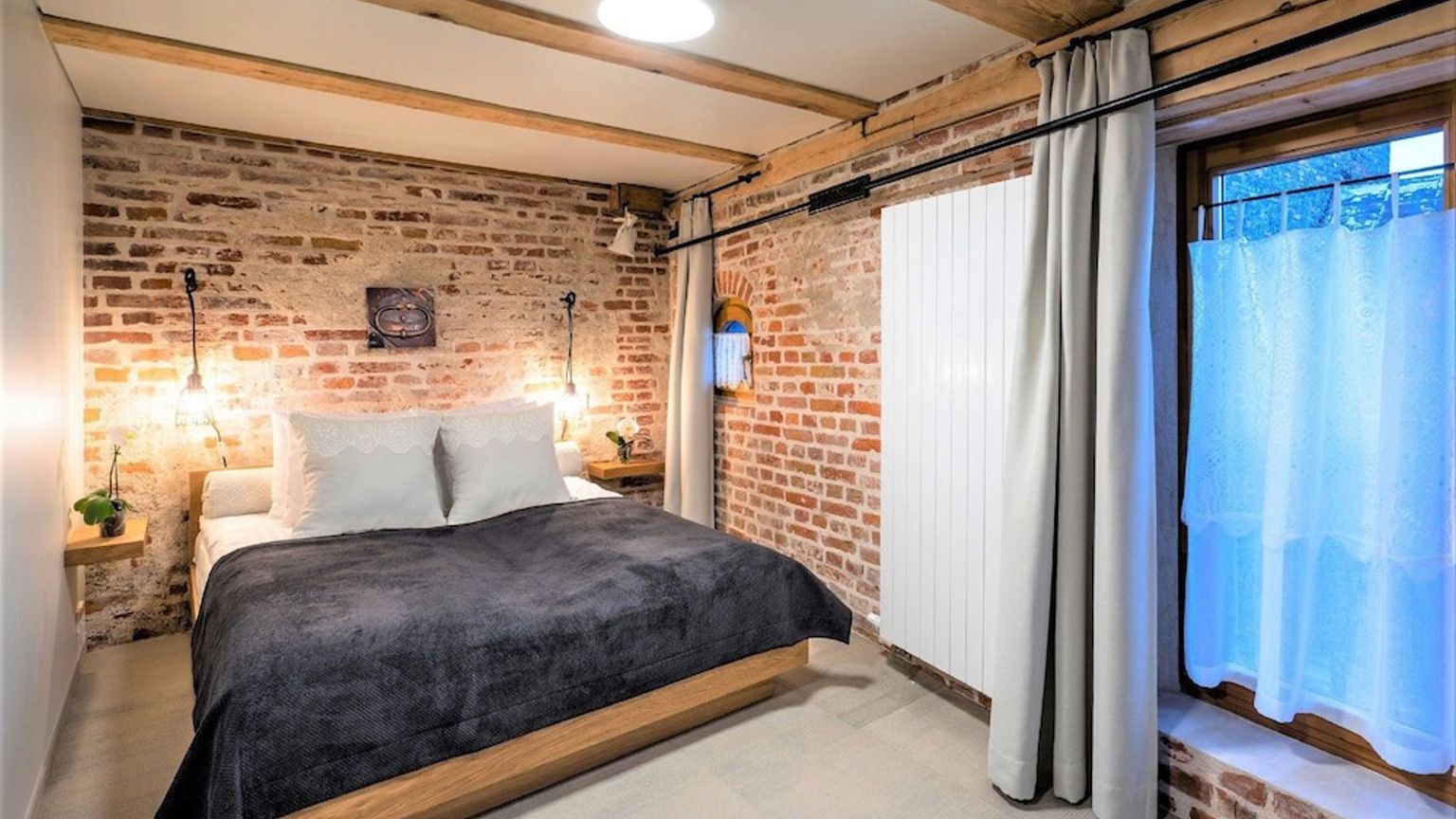 ett sovrum med en tegelvägg, en säng, ett fönster och en radiator