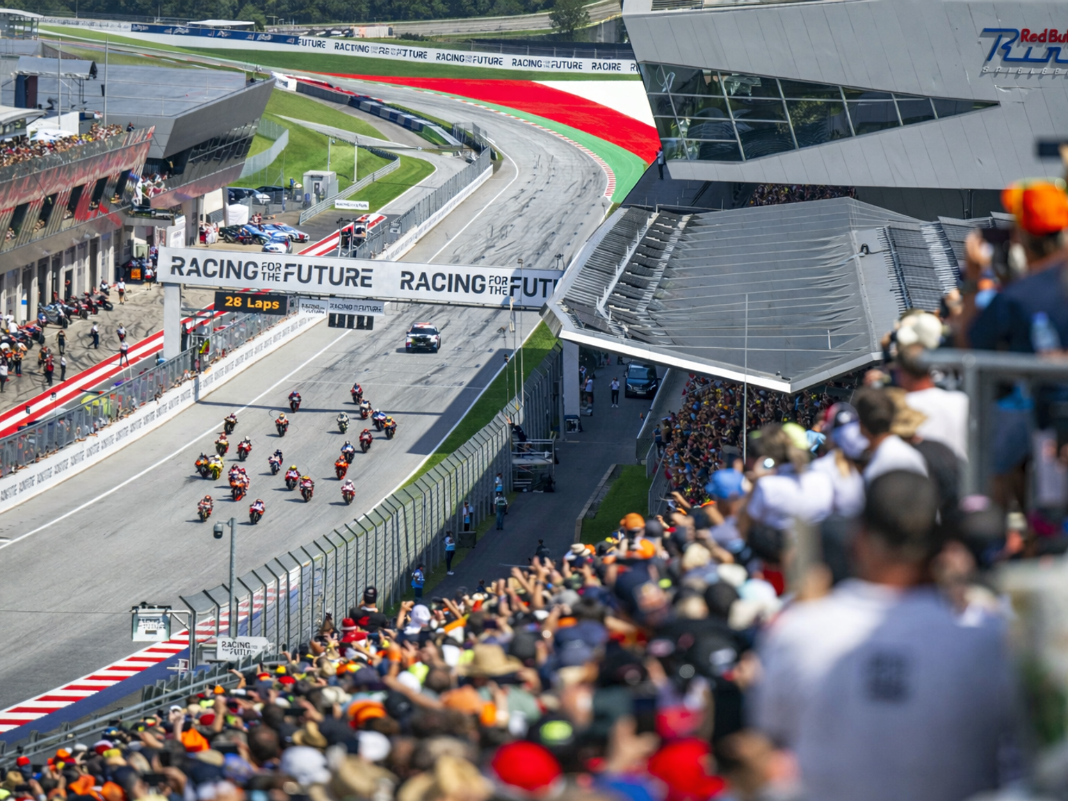 Motorsykler kappkjører på banen på Red Bull Ring, med tilskuere som fyller tribunene.