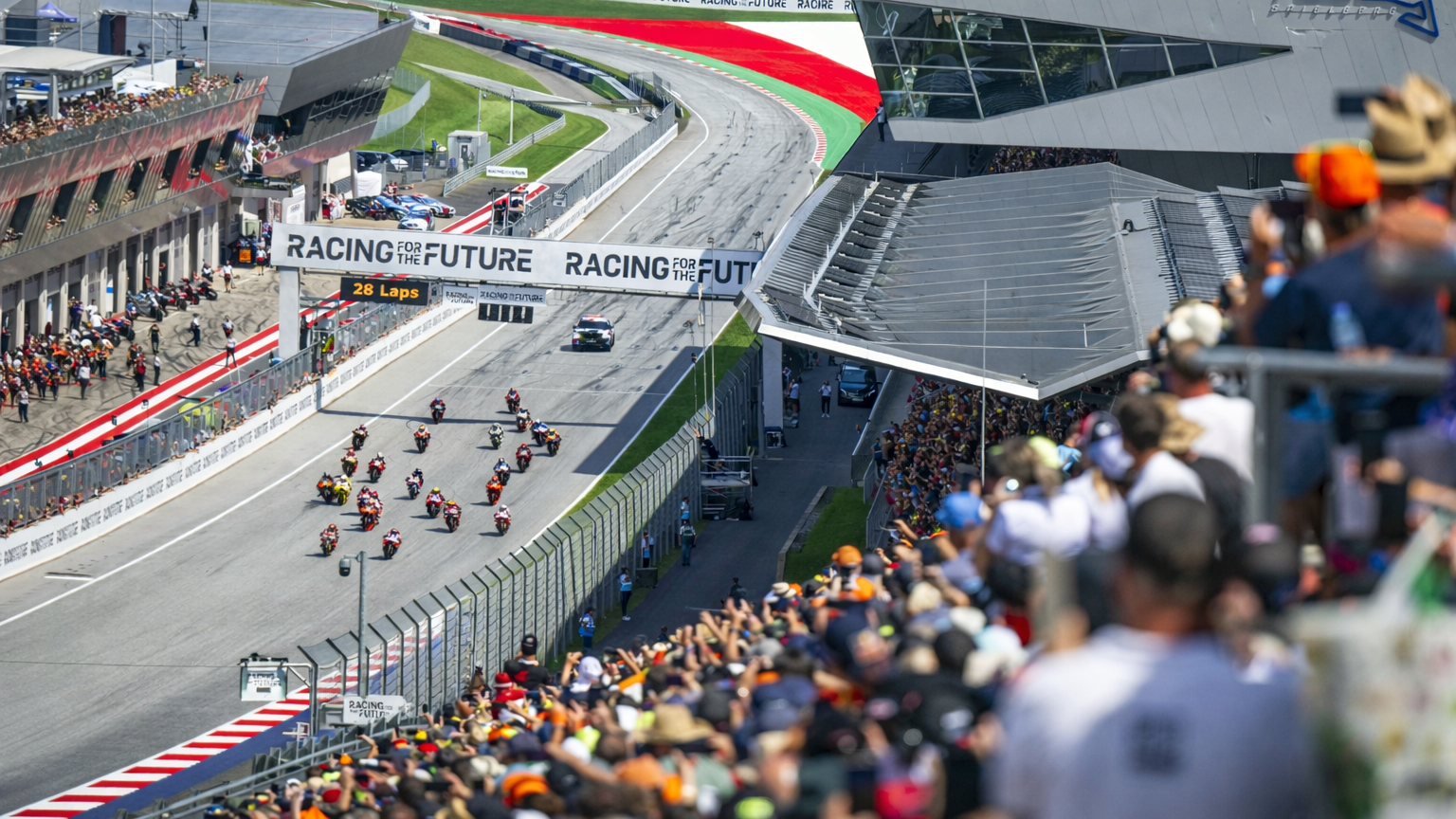 Las motocicletas corren en la pista del Red Bull Ring, con espectadores llenando las gradas.