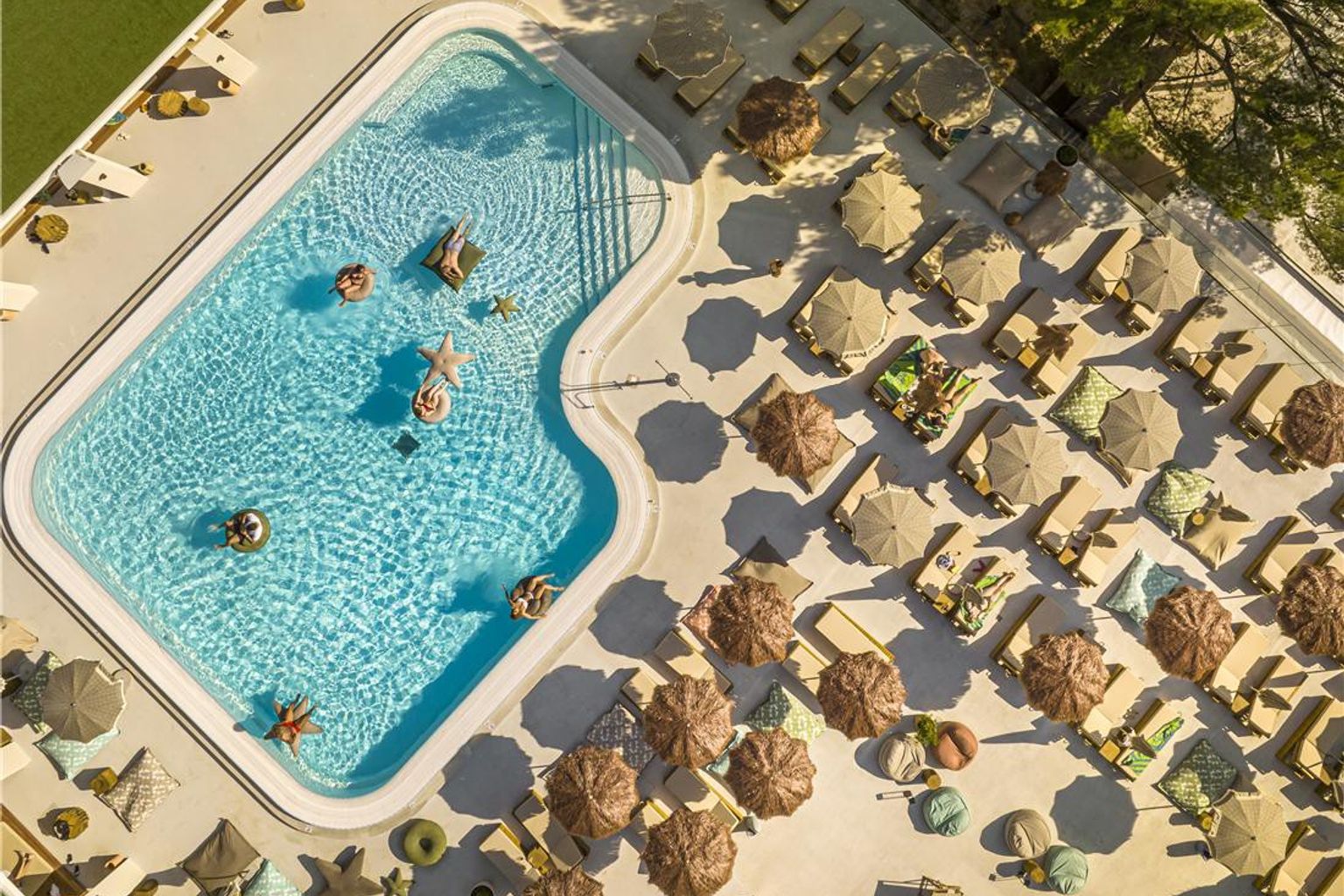 Vue aérienne d’une piscine de complexe hôtelier avec des personnes sur des bouées et une terrasse bordée de chaises longues et de parasols. Dalmacija Places Hotel by Valamar