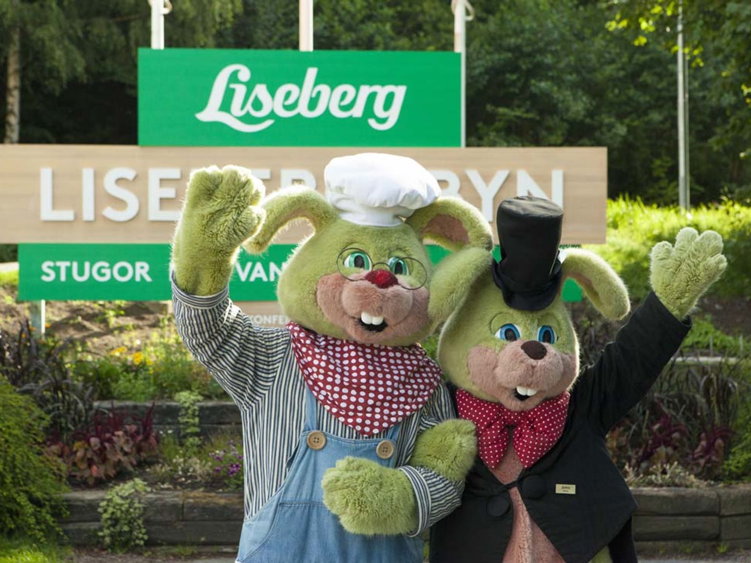 et par plysdyr står ved siden af hinanden foran et skilt