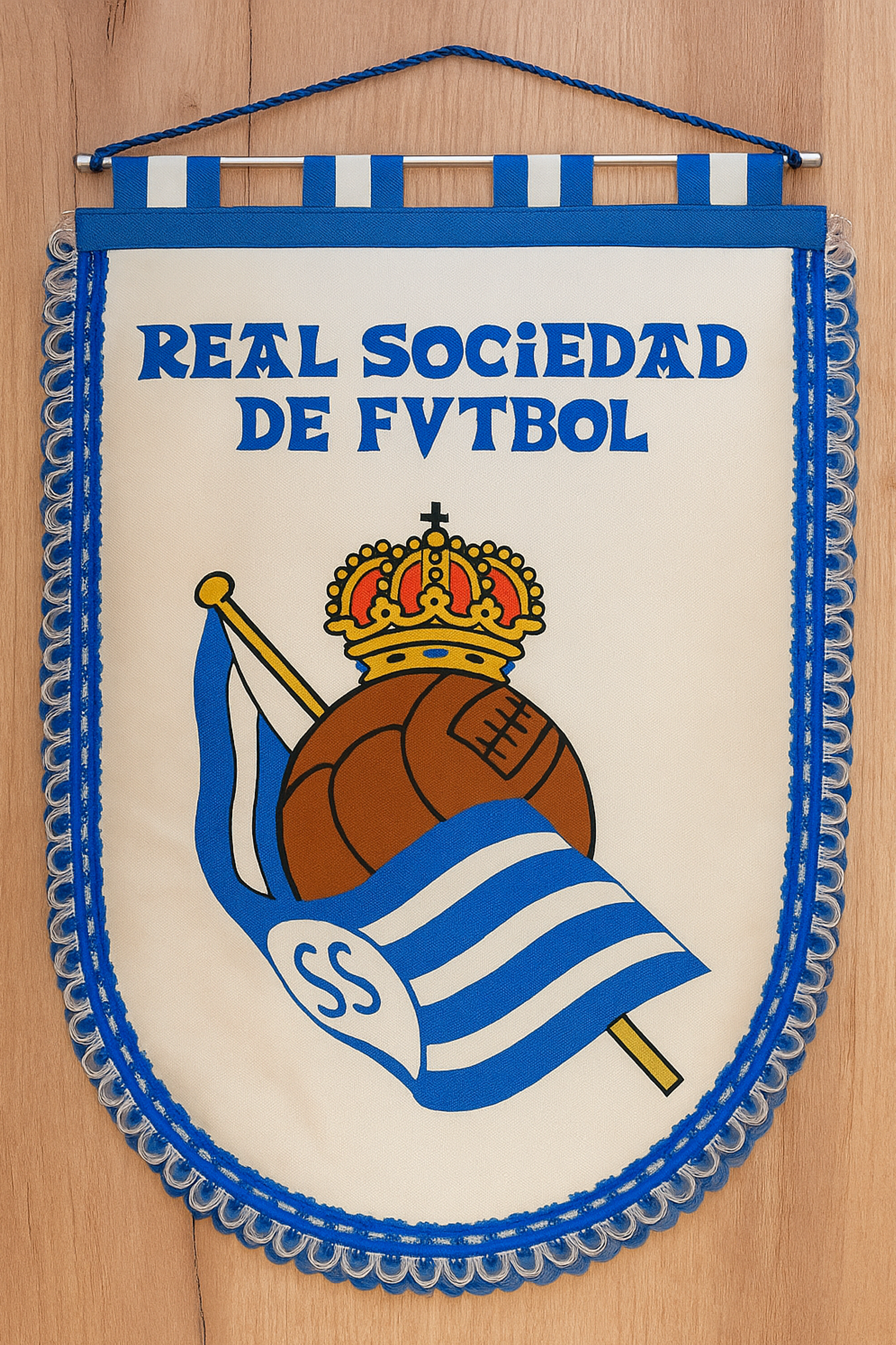A cream-colored Real Sociedad de Futbol pennant with blue trim, featuring a crowned brown football and a blue and white striped flag with "SS".