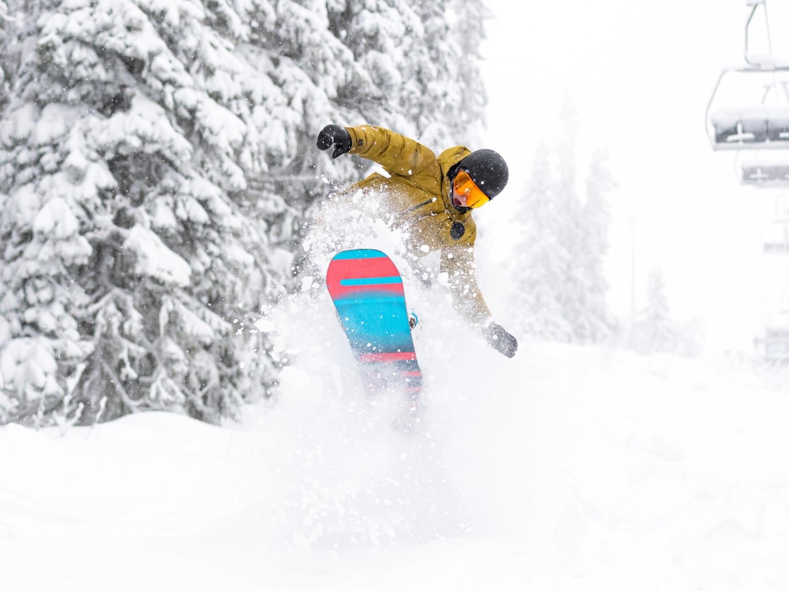 en person åker snowboard nerför en snötäckt sluttning
