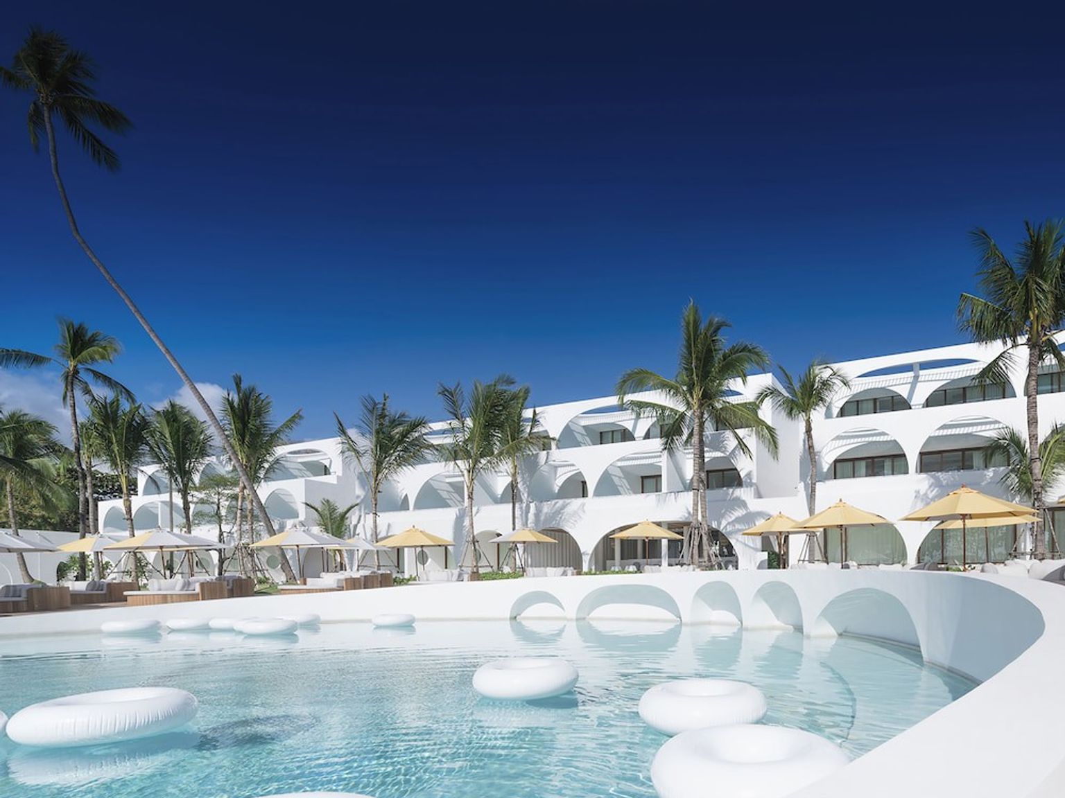 duży biały budynek z basenem przed nim