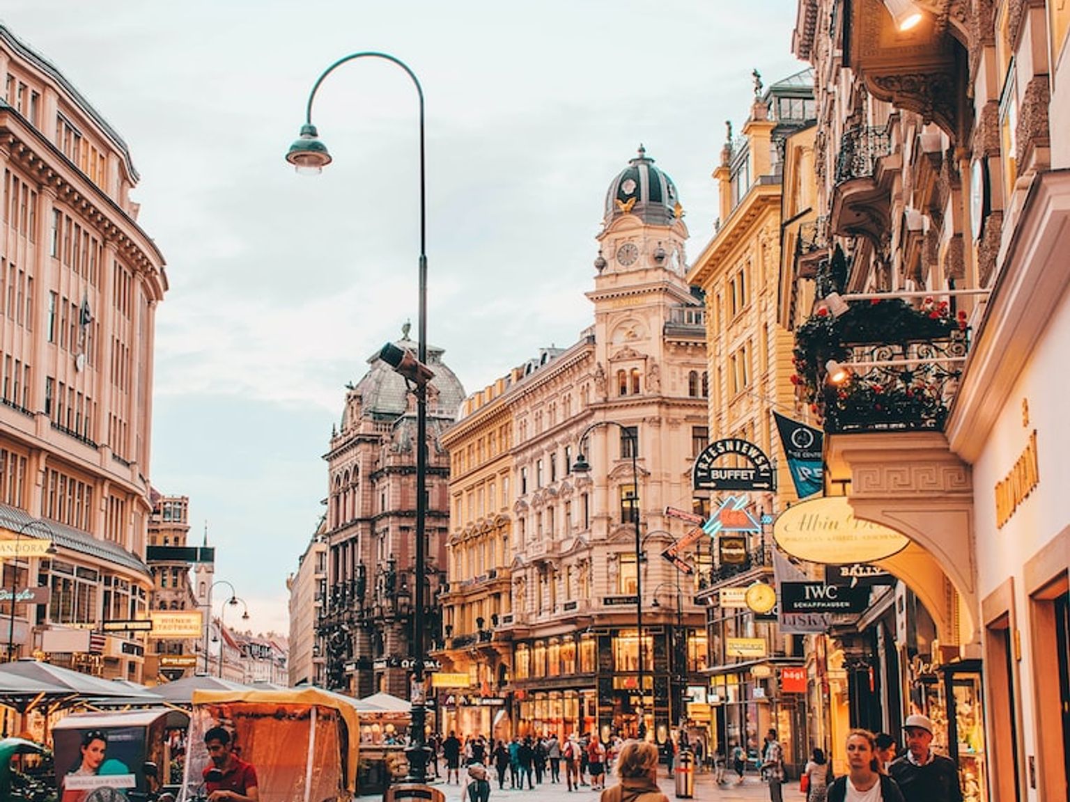 a blue Berlitz sign hangs above a busy city street in Vienna