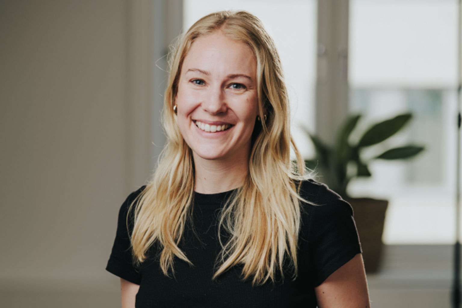 A smiling young woman with long blonde hair in a black shirt.