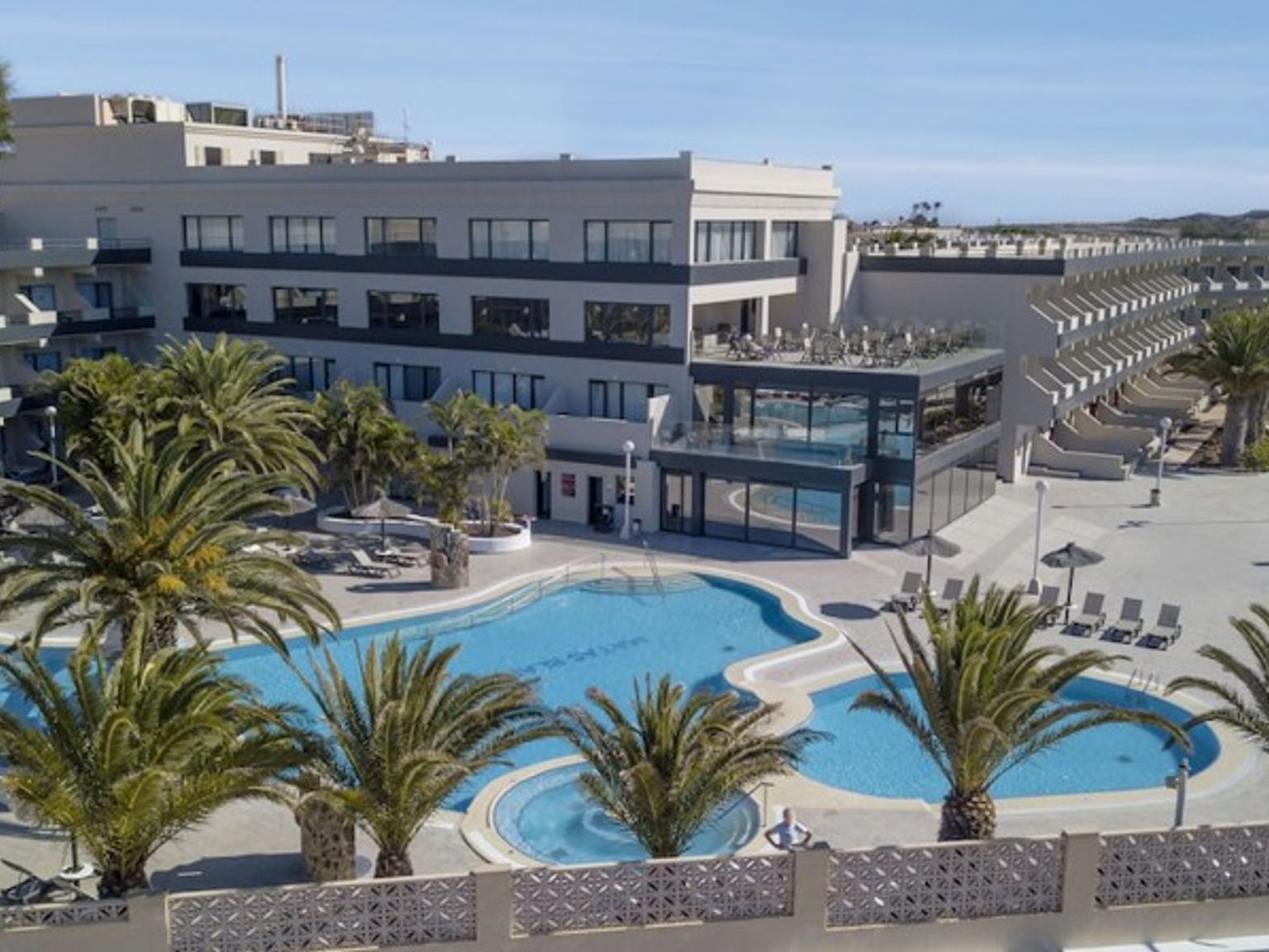 en flygvy över ett hotell med en stor pool omgiven av palmer
