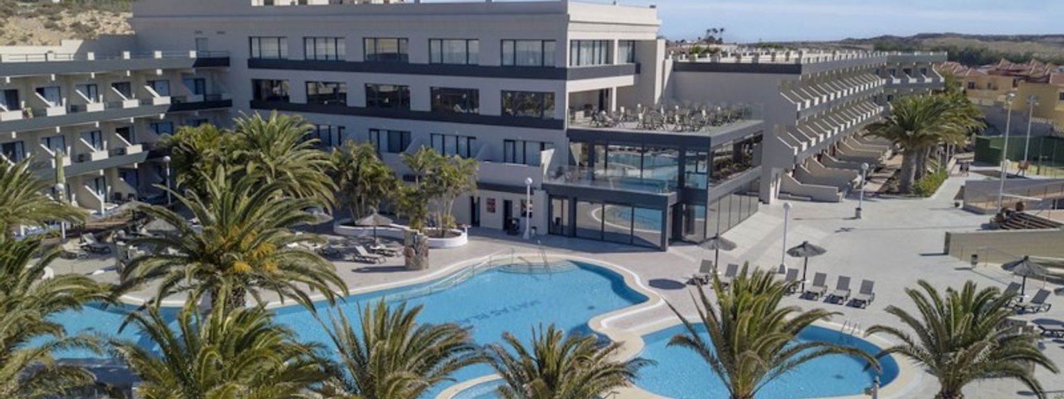 en flygvy över ett hotell med en stor pool omgiven av palmer