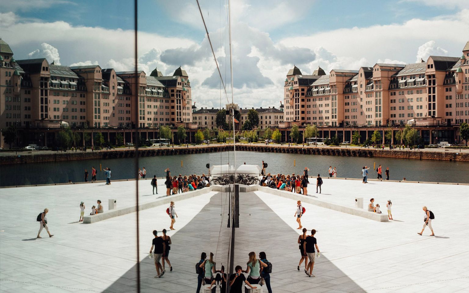 en gruppe mennesker står foran en stor bygning ved siden af et vandområde