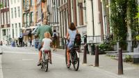 en familie sykler nedover en bygate.