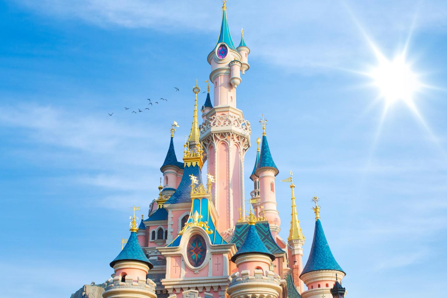 ett stort rosa och blått slott mot en blå himmel med solen som skiner genom molnen