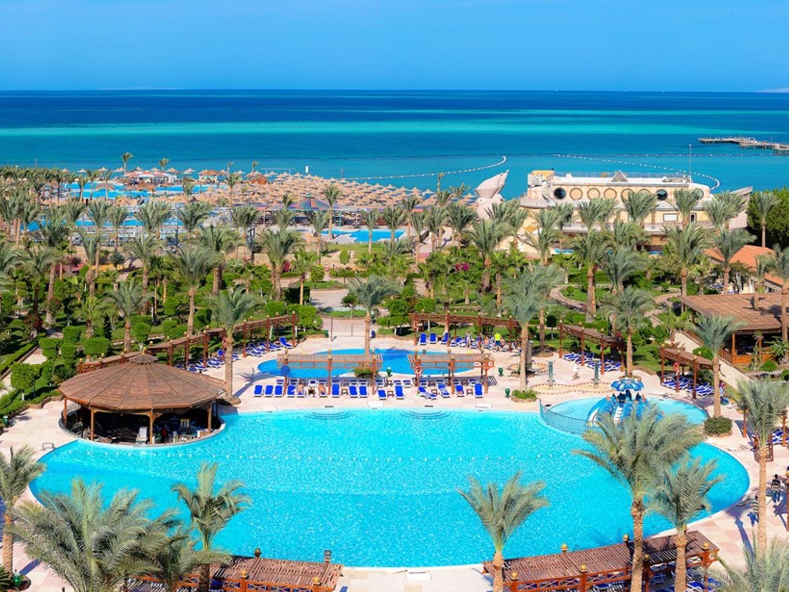 en flygvy över en tropisk resort med en stor pool omgiven av palmer