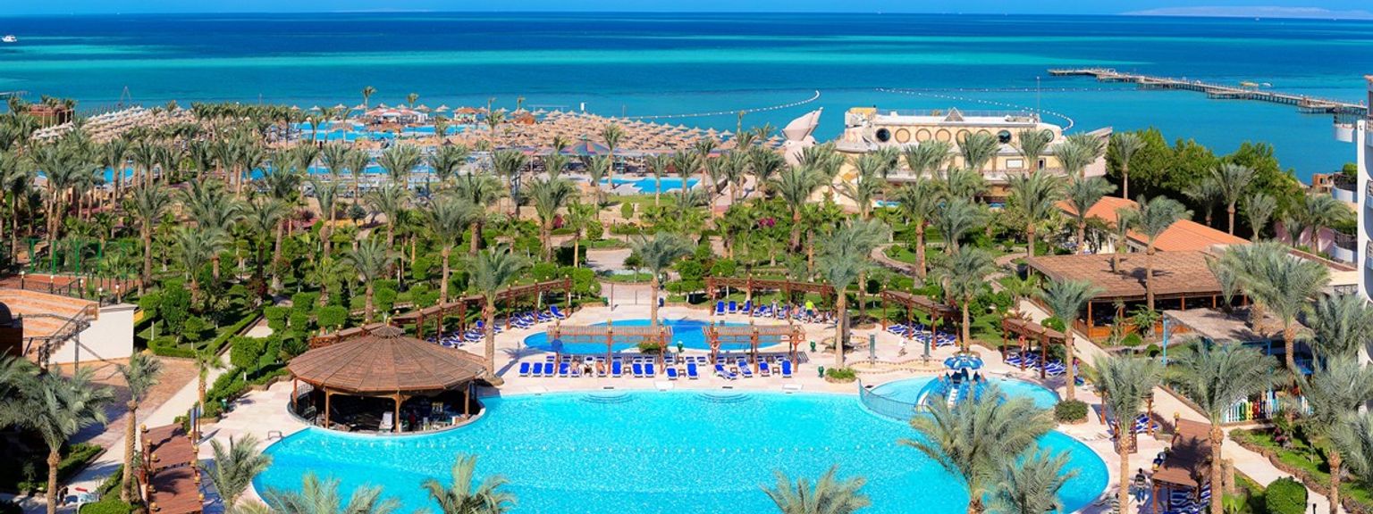 en flygvy över en tropisk resort med en stor pool omgiven av palmer