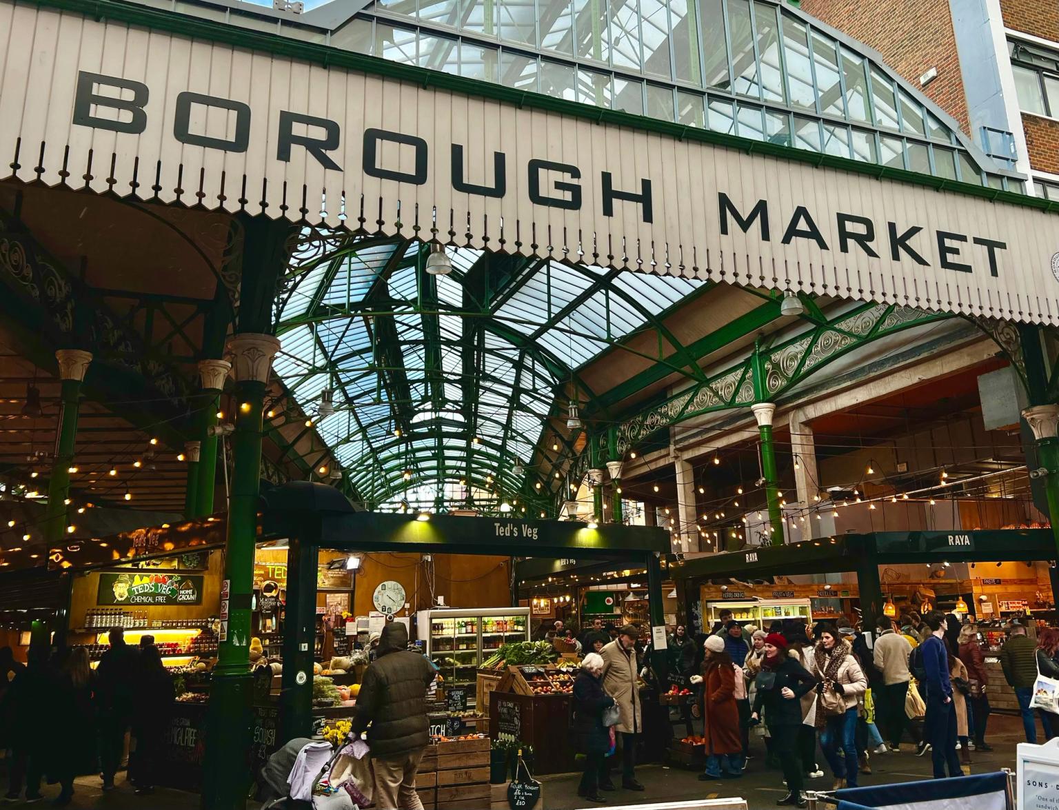 en grupp människor står under en skylt i London som säger borough market.