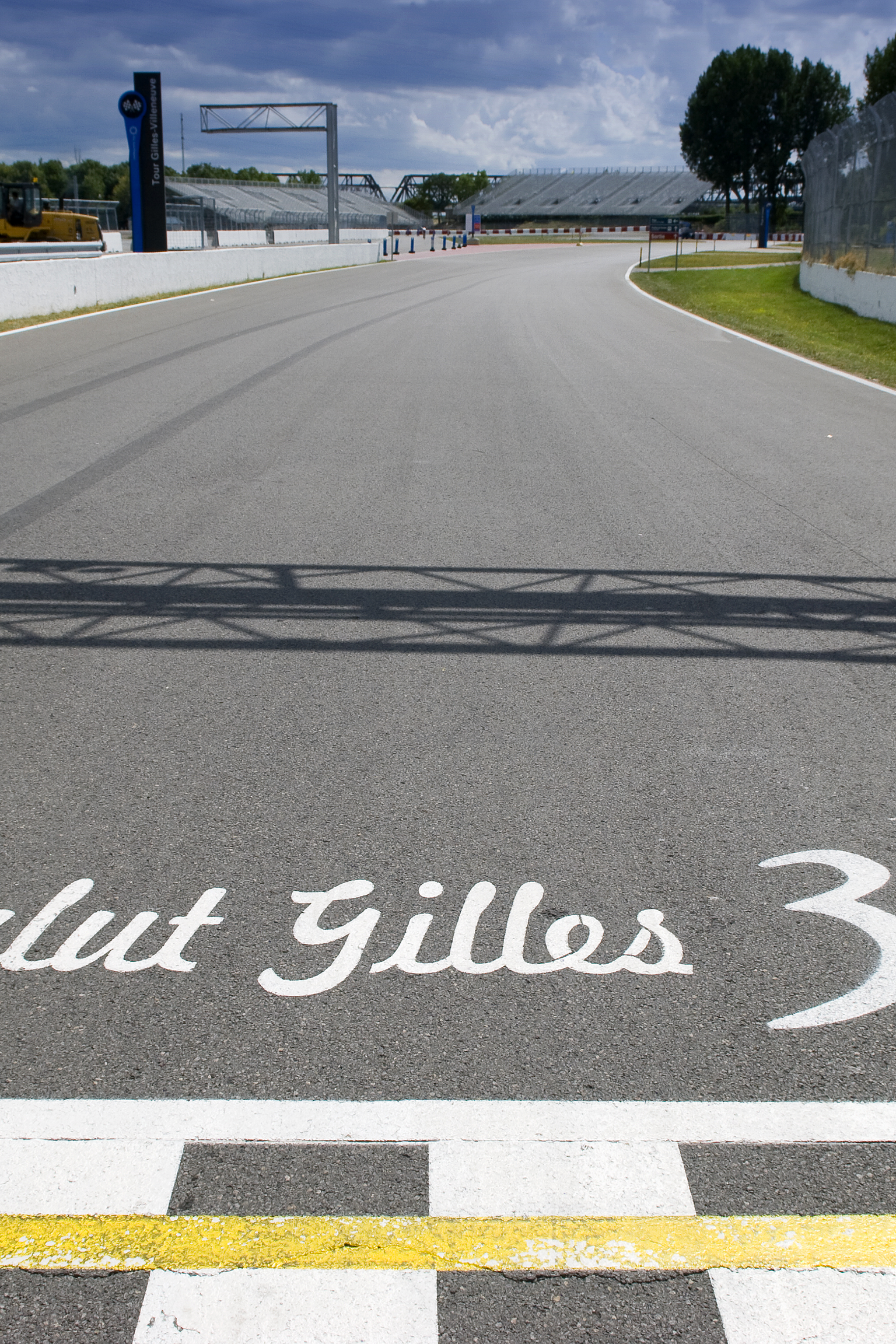 Tor wyścigowy z szachownicową linią mety oraz napisem „Salut Gilles 30 ANS” namalowanym na asfalcie.