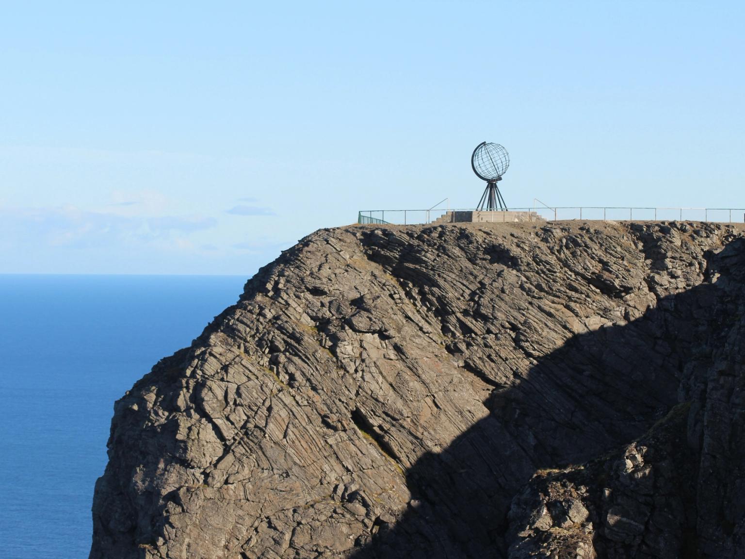 en stor klippeklippe med udsigt over havet med et ur på toppen af det