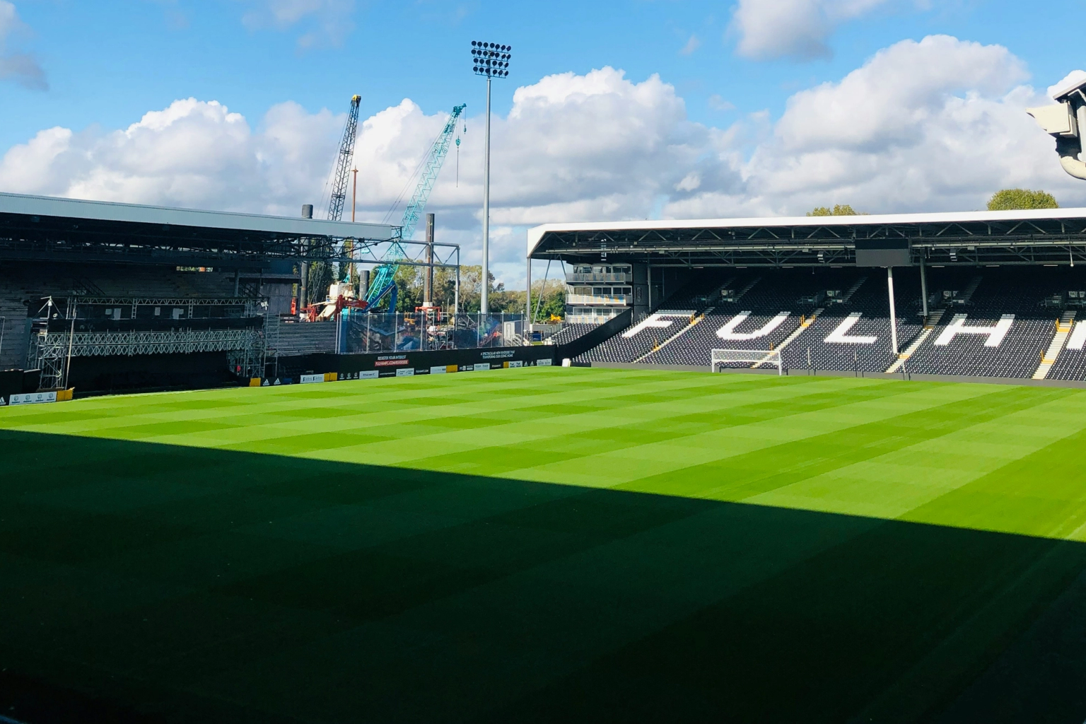 ein Mann steht auf einem Fußballfeld vor einem Banner, das sagt 'wir sind fulham'