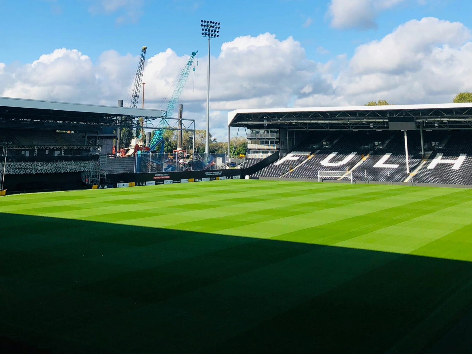 en mann står på en fotballbane foran et banner som sier 'vi er fulham'