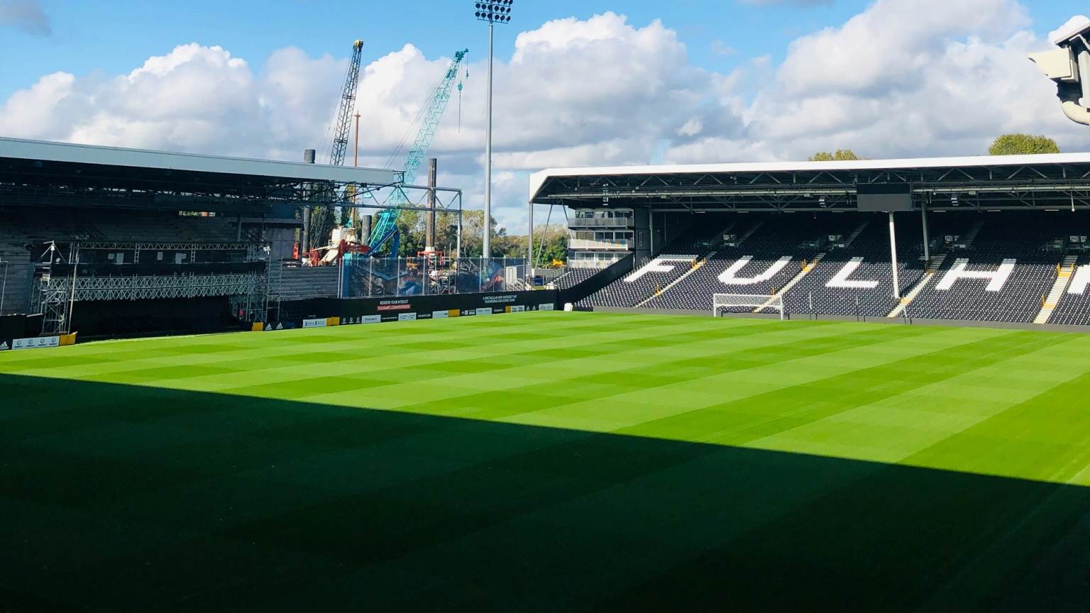 ein Mann steht auf einem Fußballfeld vor einem Banner, das sagt 'wir sind fulham'