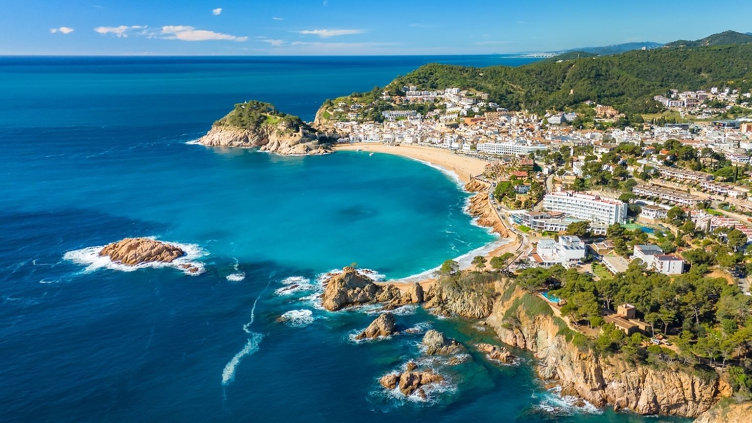 Vue aérienne d’une ville côtière avec une plage de sable, une eau turquoise et des affleurements rocheux. Tossa de Mar, Espagne