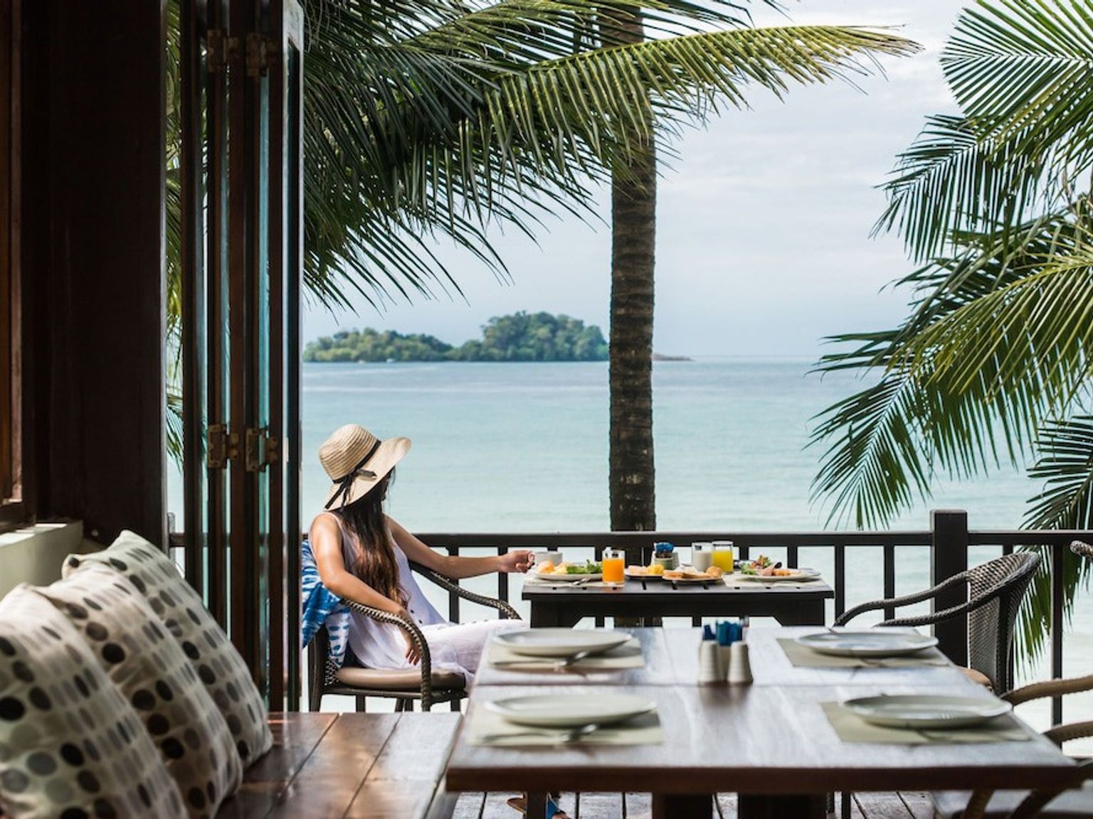 eine Frau sitzt an einem Tisch mit Blick auf das Meer