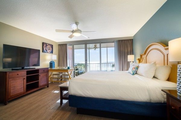 et hotellrom med en king size seng, en flatskjerm-tv og en balkong med utsikt over havet.