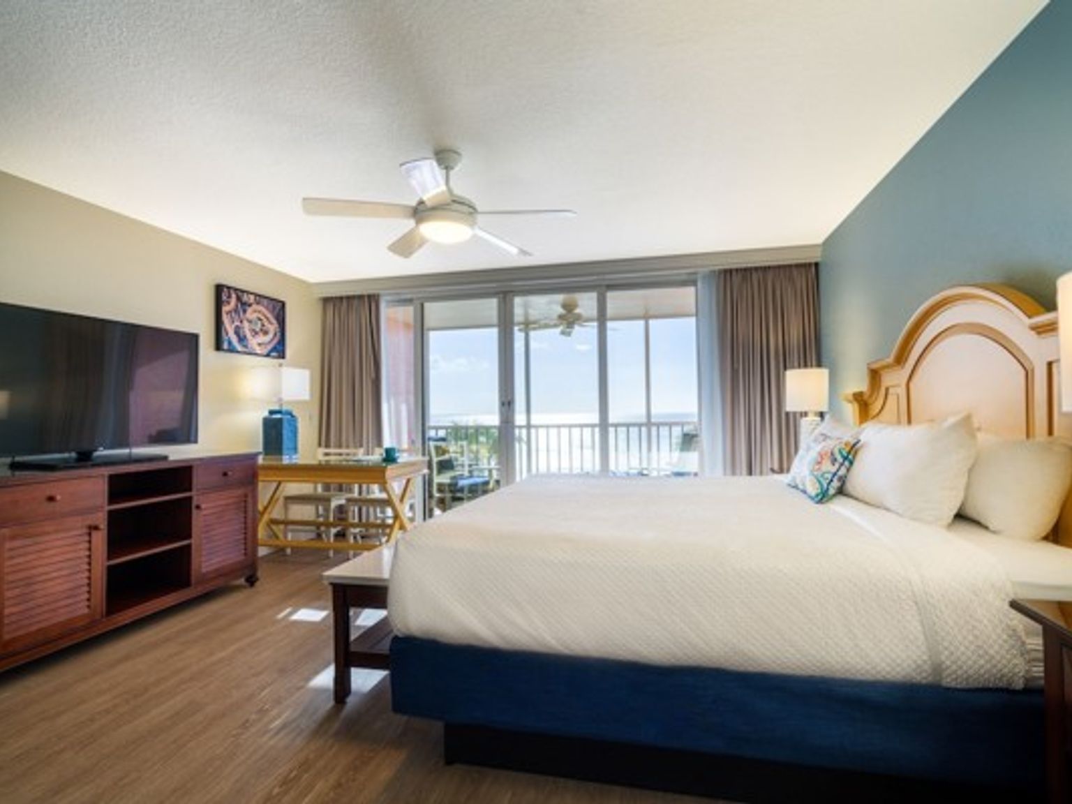 et hotellrom med en king size seng, en flatskjerm-tv og en balkong med utsikt over havet.