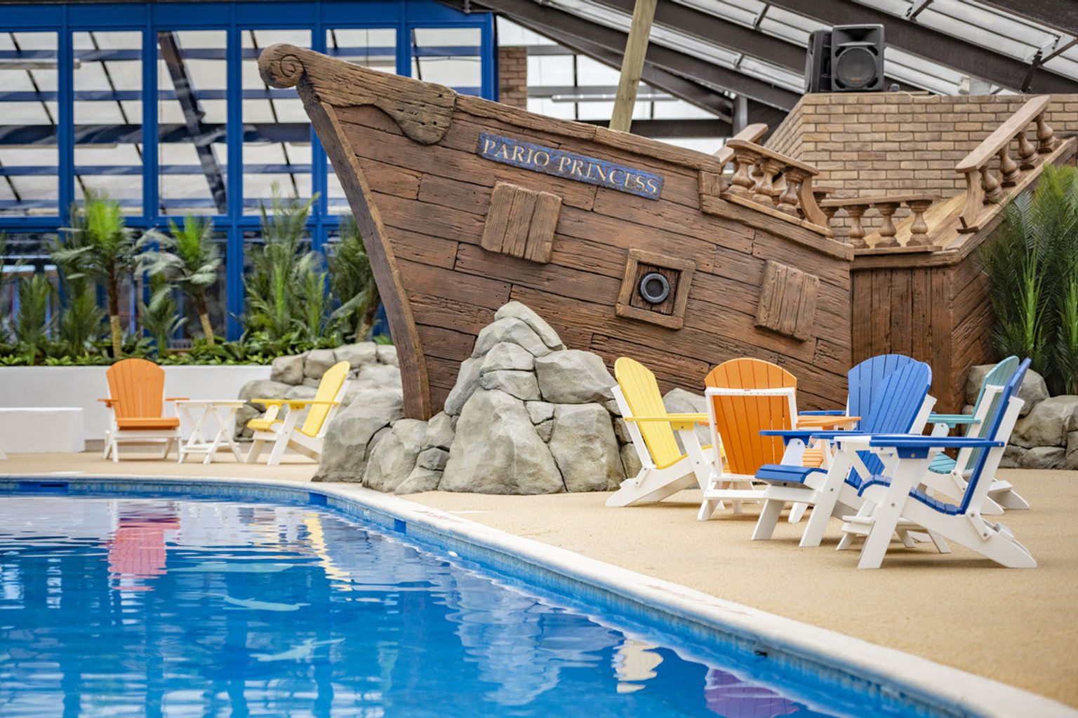 a swimming pool with chairs and a pirate ship in the background