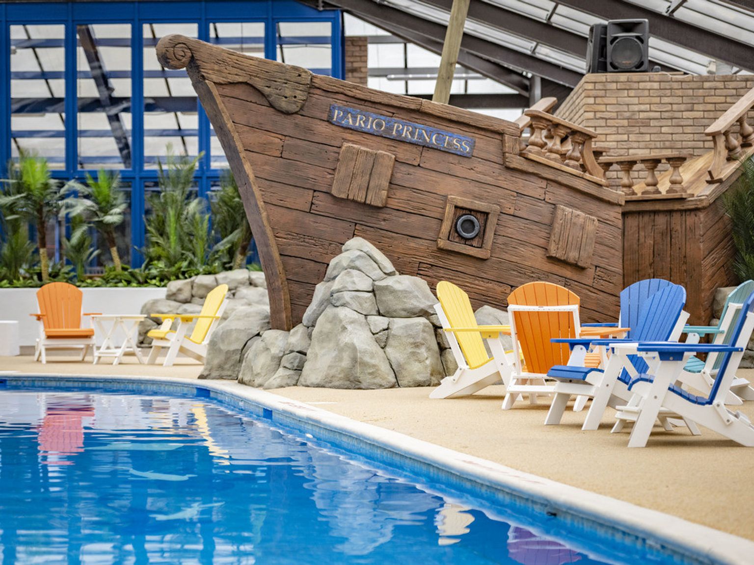 a swimming pool with chairs and a pirate ship in the background