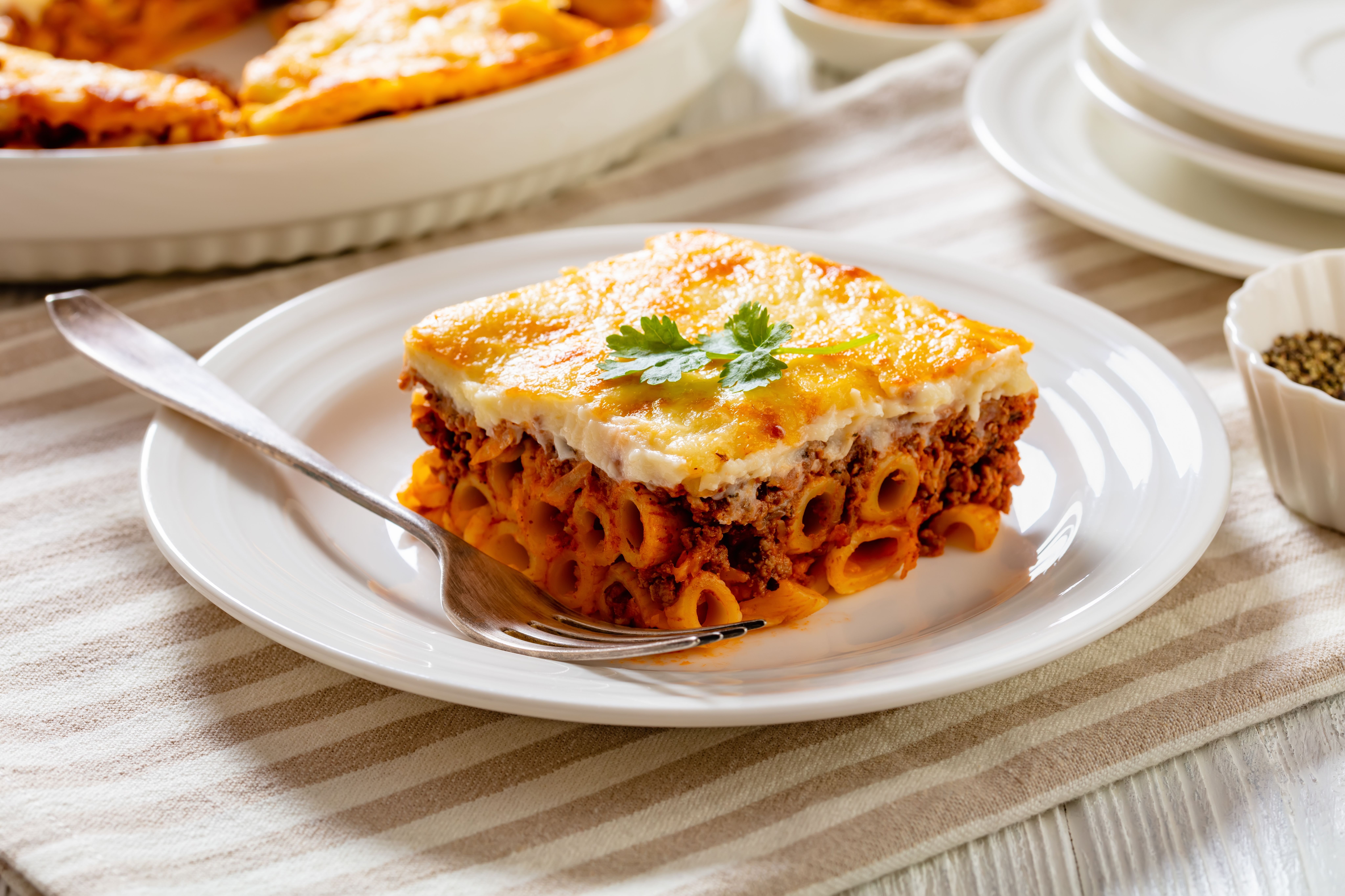 a slice of lasagna on a white plate with a fork