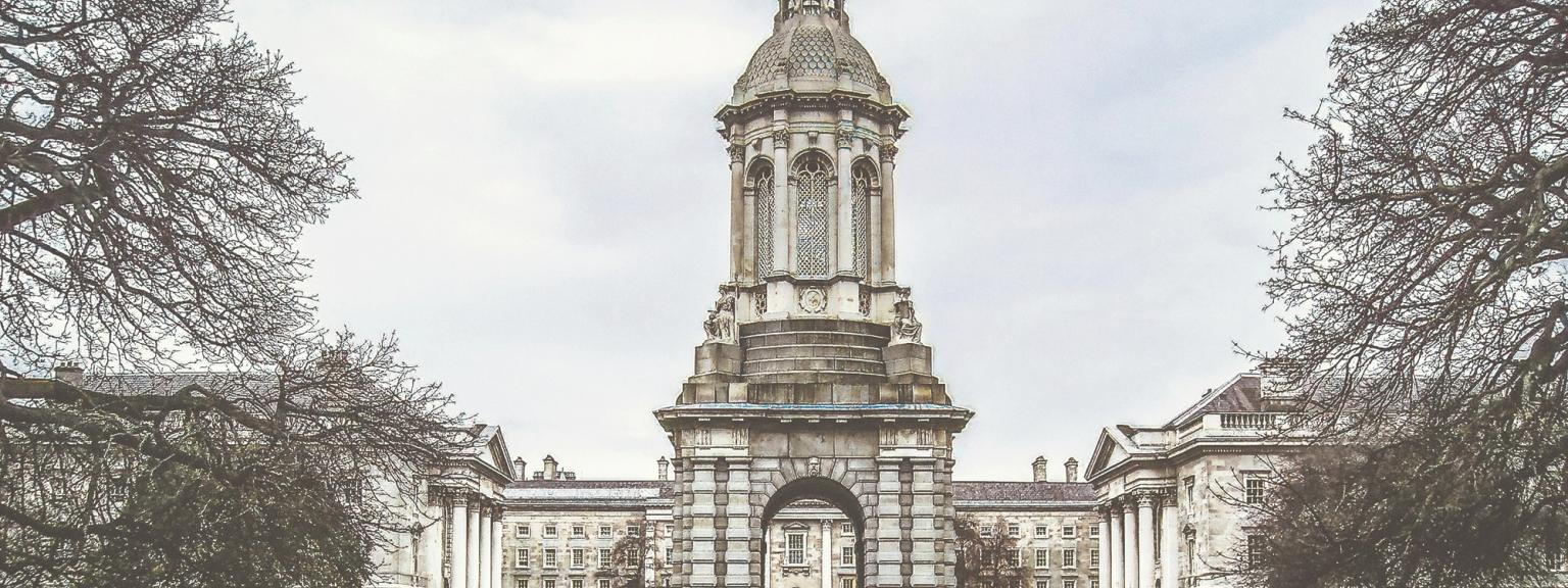 a large building with a clock tower in the middle of a park, Dublin