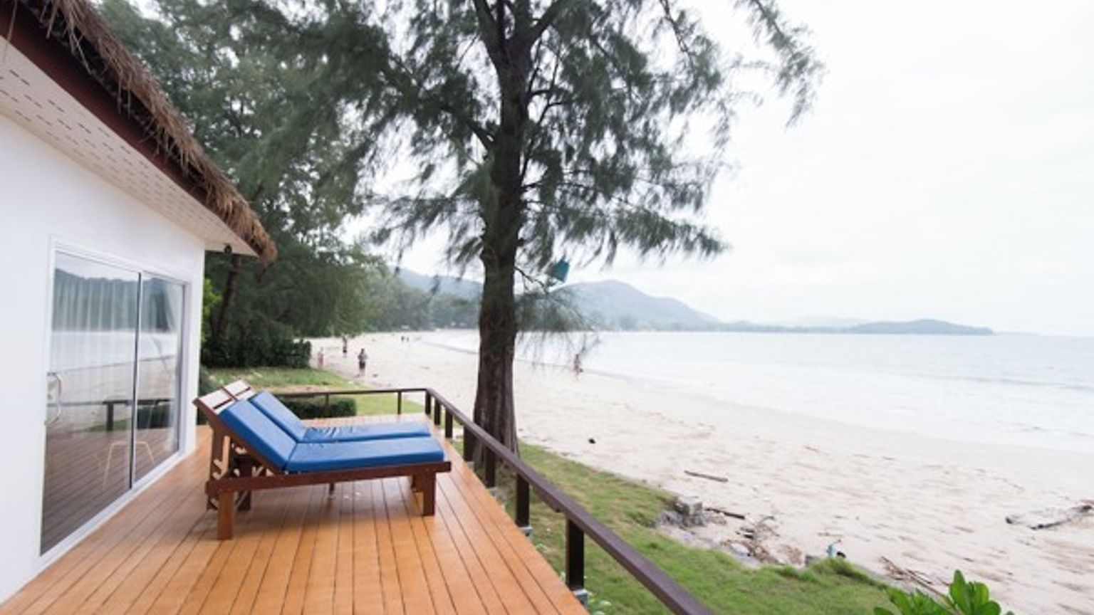 en träaltan med stolar och utsikt över stranden