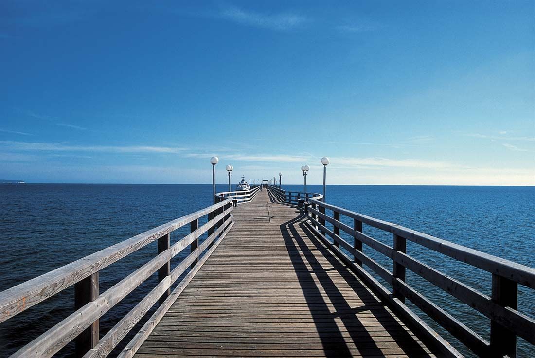 ein langer Holzsteg, der an einem sonnigen Tag ins Meer führt
