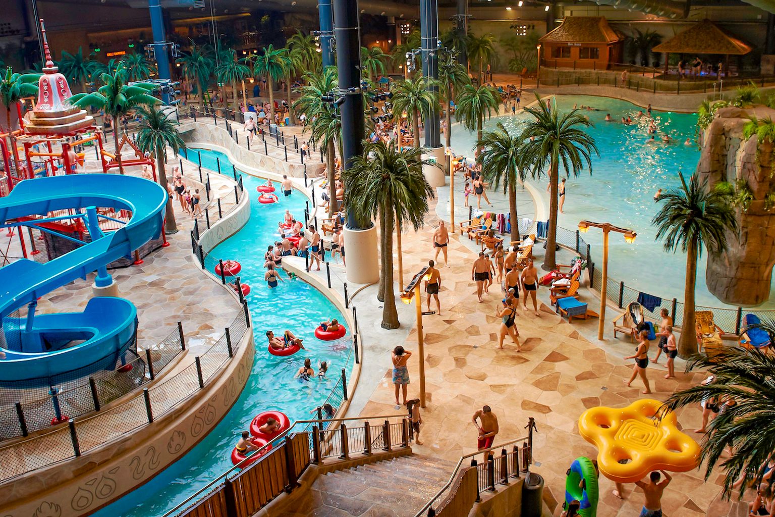 Zdjęcie z wnętrza największego parku wodnego w Skandynawii, Aquadome w Lalandia. Zdjęcie pokazuje obszar z basenami, zjeżdżalniami wodnymi i wieloma ludźmi.