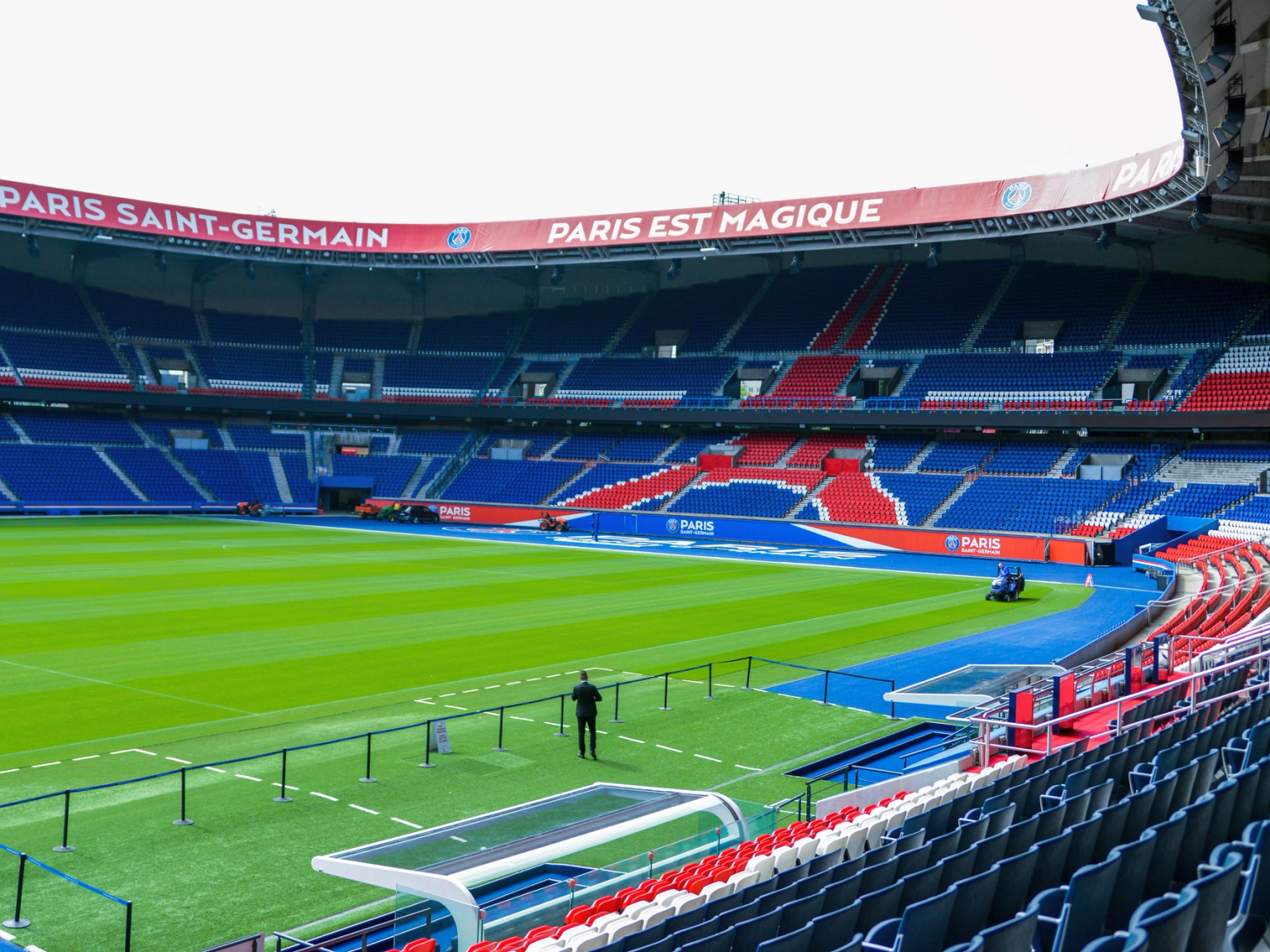 Estádio de futebol vazio do Paris Saint-Germain com um campo verde e assentos vermelhos e azuis.
