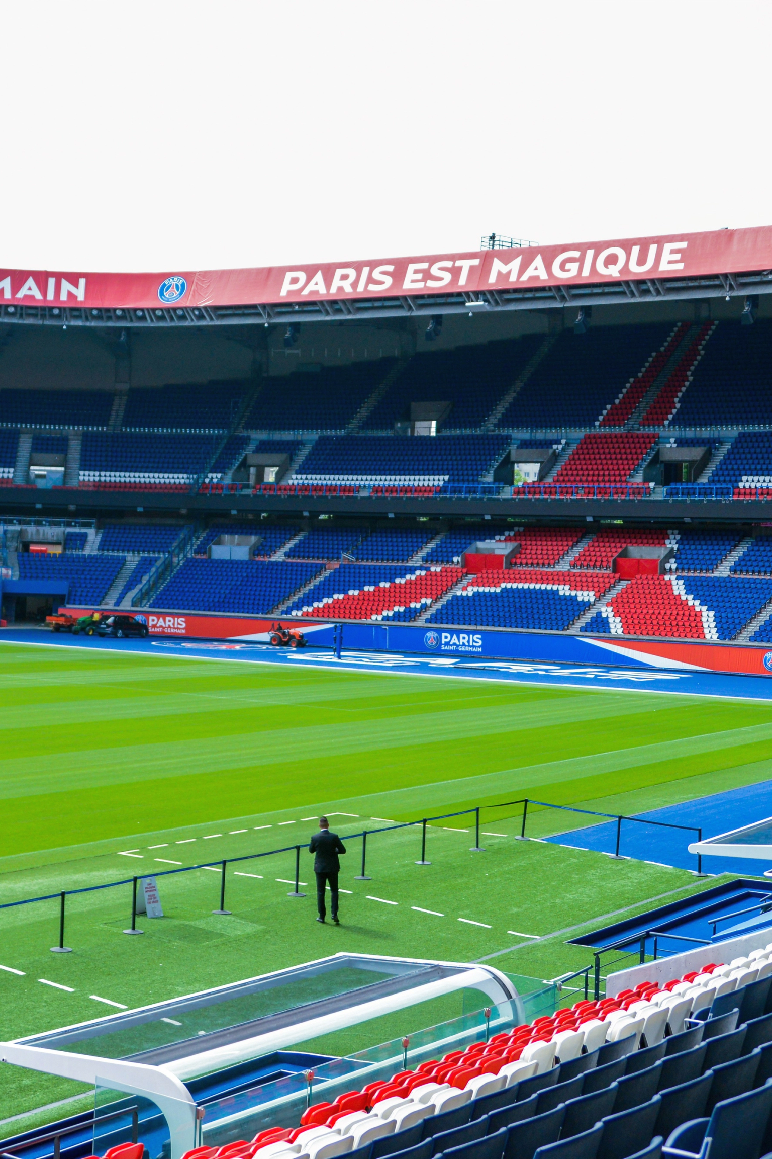 Estádio de futebol vazio do Paris Saint-Germain com um campo verde e assentos vermelhos e azuis.