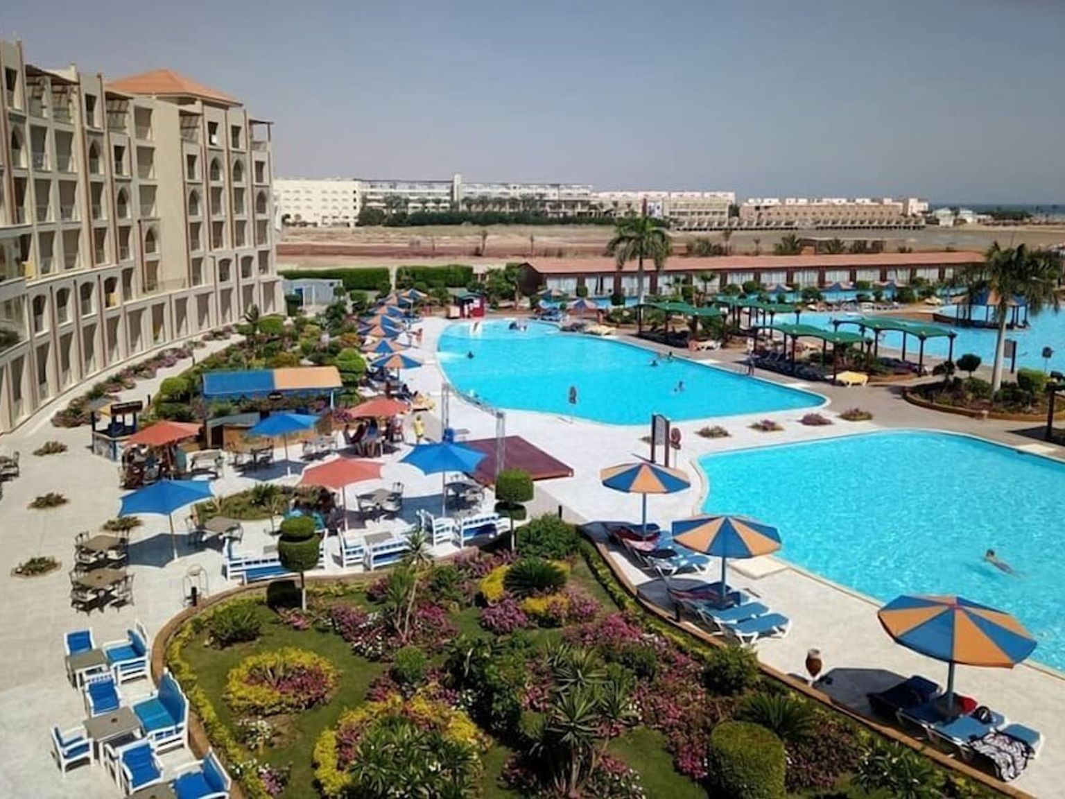 en luftig utsikt over et stort svømmebasseng omgitt av paraplyer og stoler