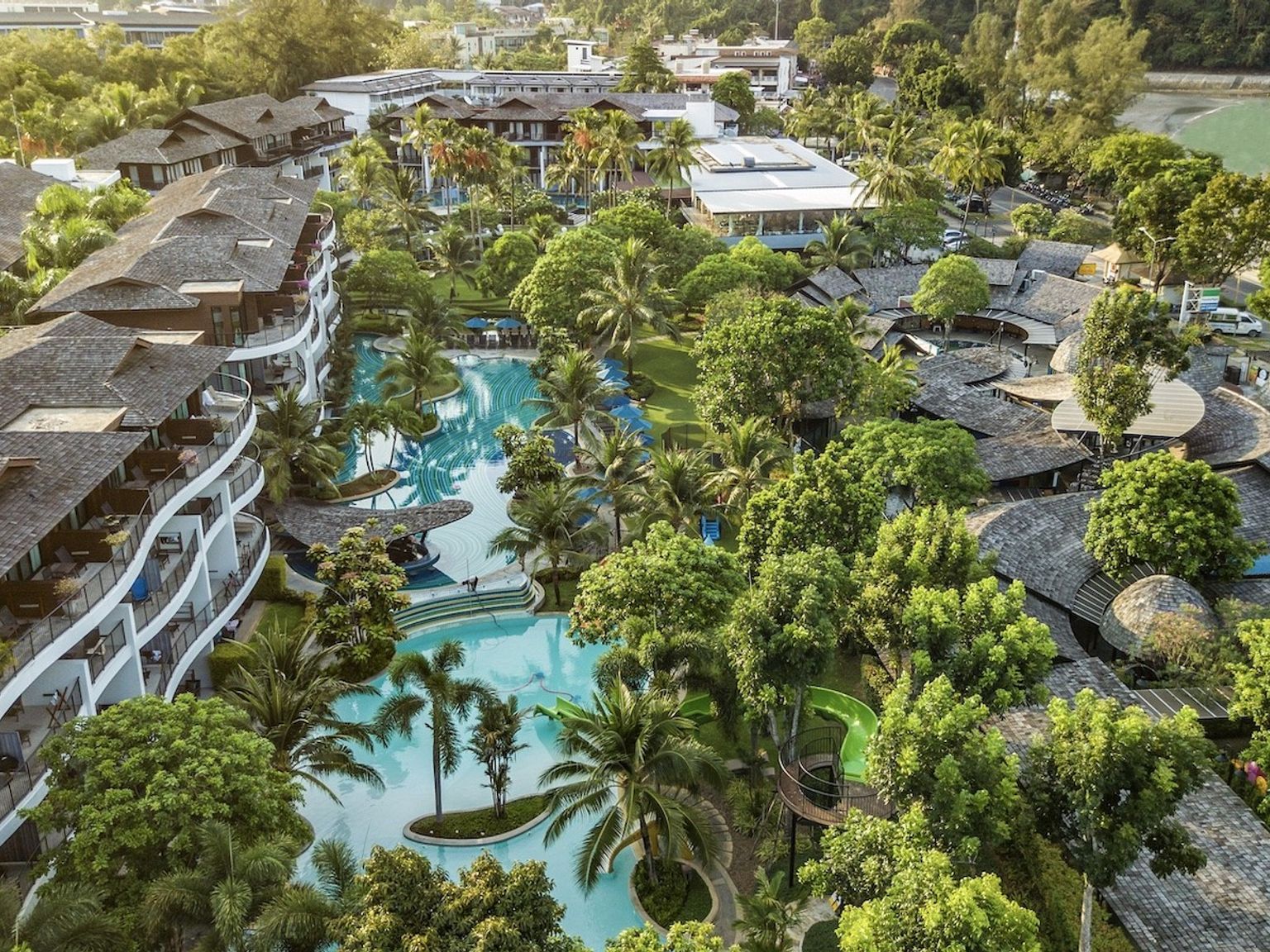 een luchtfoto van een tropisch resort met een groot zwembad omringd door palmbomen.