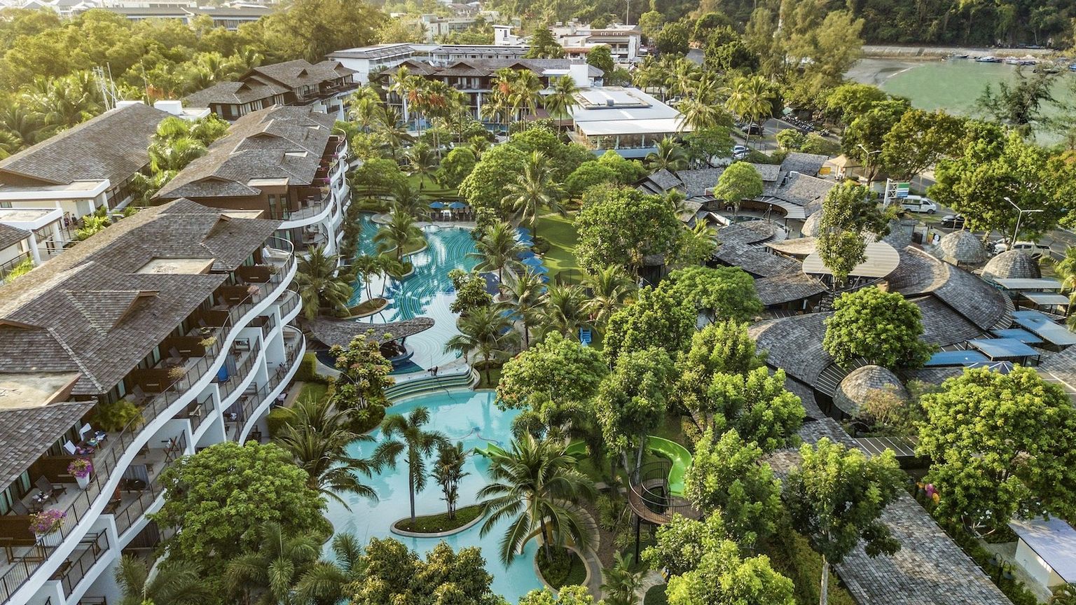 en flygvy över en tropisk resort med en stor swimmingpool omgiven av palmer
