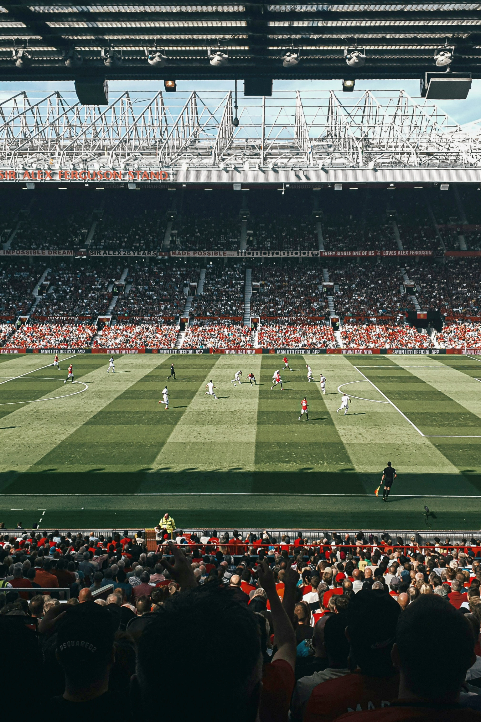 En fotballkamp på et fullsatt stadion med spillere på en stripete grønn bane.
