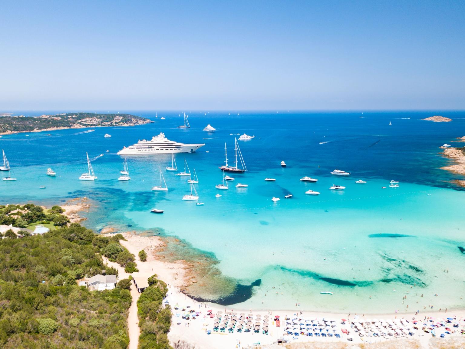 et luftfoto av en tropisk strand med båter i vannet.