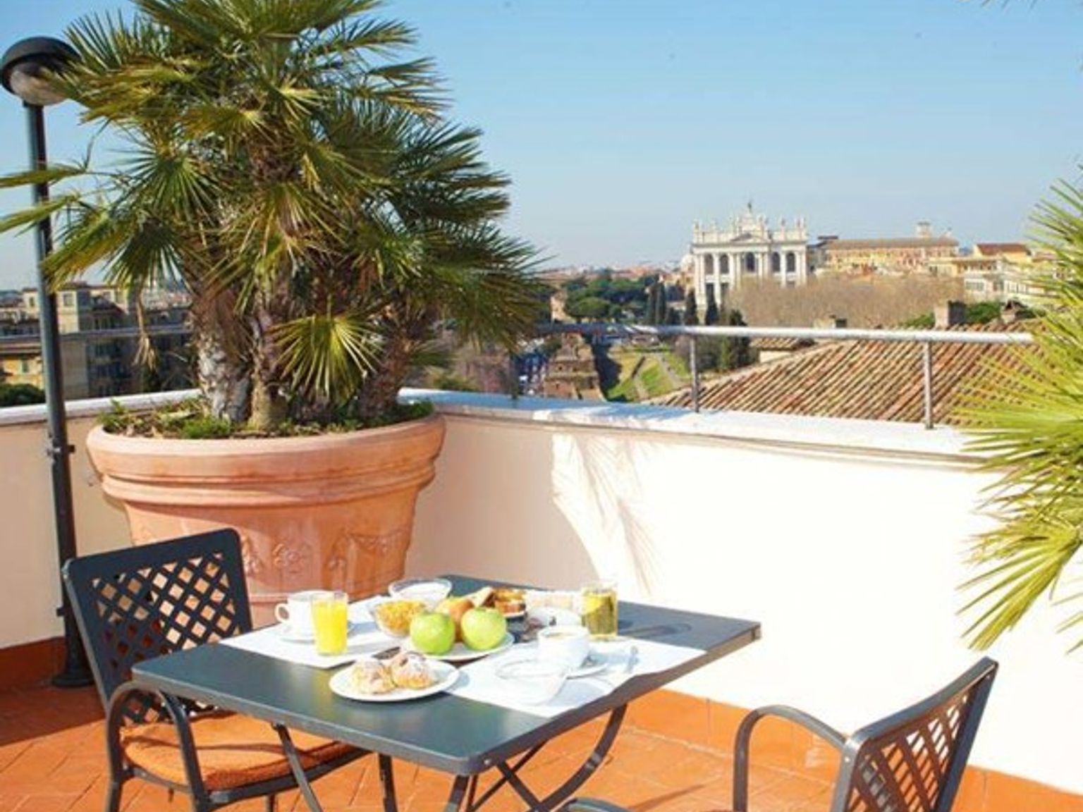 ett bord och stolar på en balkong med en krukväxt i bakgrunden