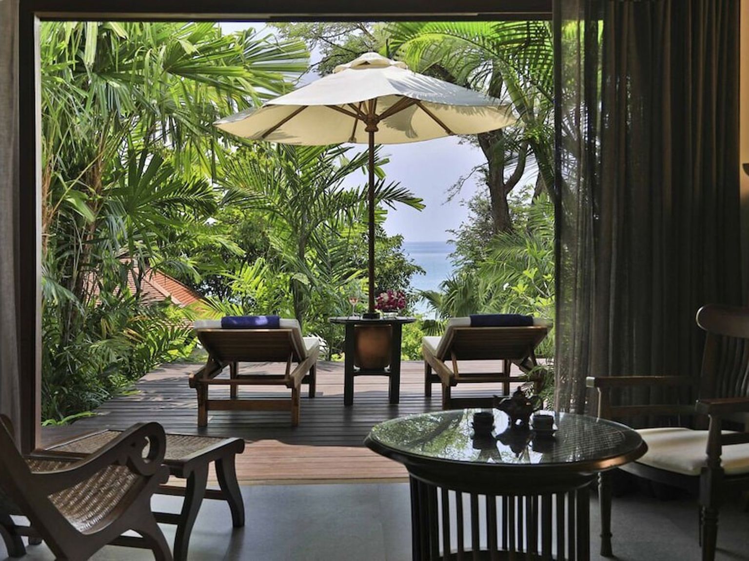 ein Raum mit Stühlen, einem Tisch, einem Regenschirm und Blick auf das Meer.