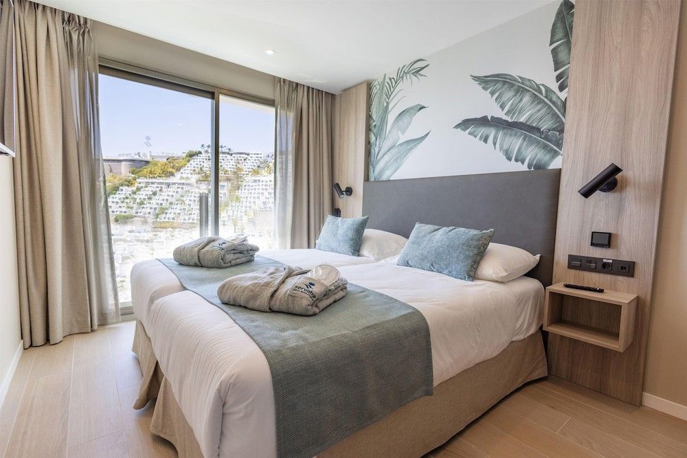 Et moderne dobbeltværelse med en tropisk vægmaleri og en naturskøn udsigt over bakkerne fra vinduet.