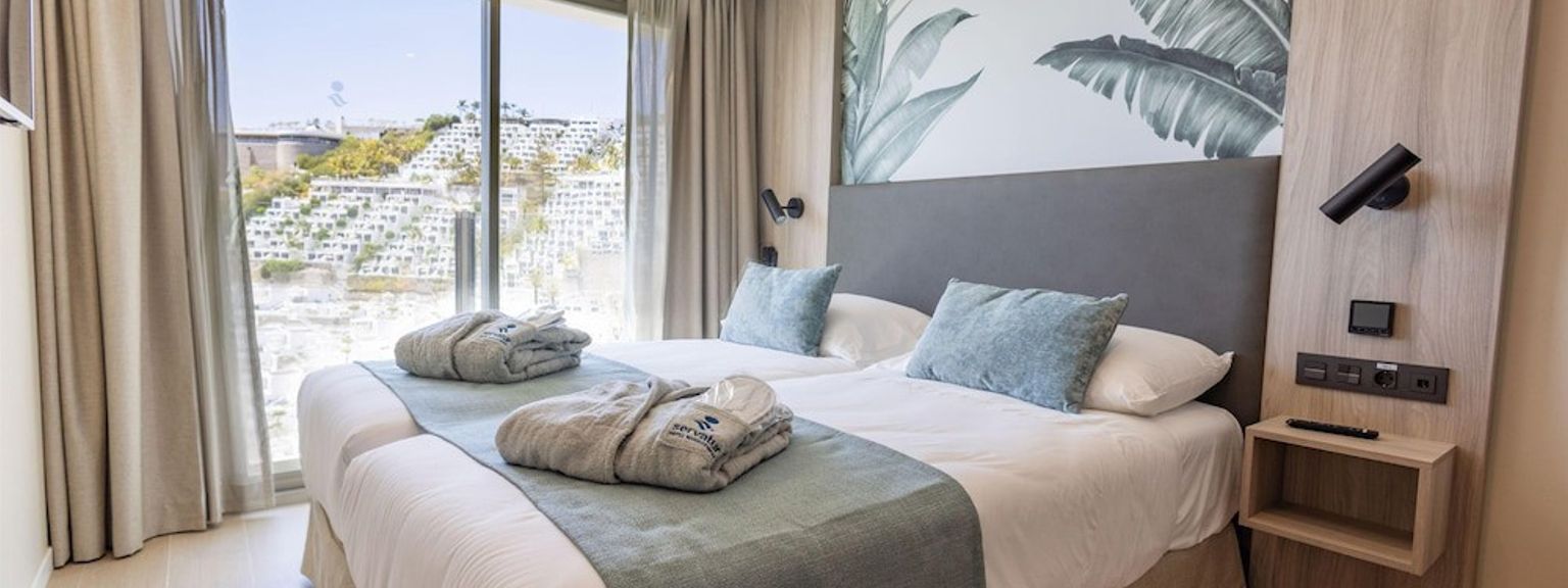 Et moderne dobbeltrom med et tropisk veggmaleri og en naturskjønn utsikt over åsene fra vinduet.