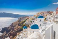 Witte klifgebouwen met blauwe koepels in Santorini met uitzicht op de Egeïsche Zee.