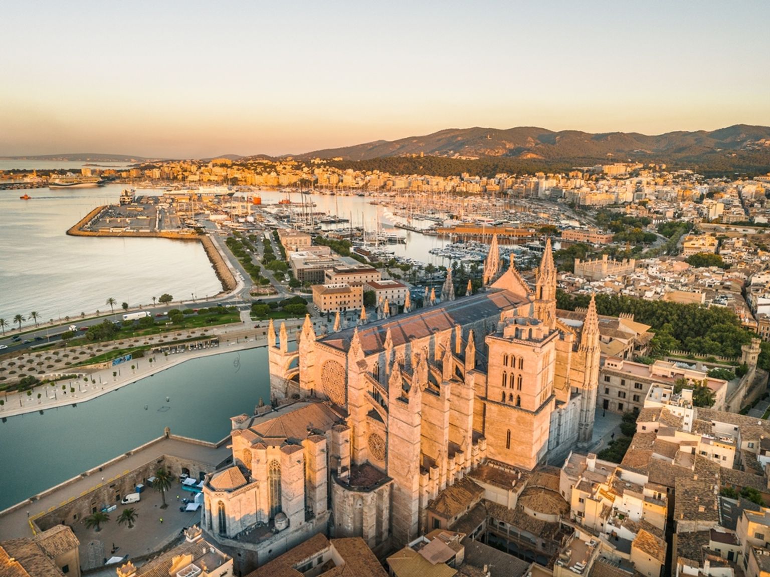 Luftaufnahme einer großen gotischen Kathedrale zur goldenen Stunde mit Blick auf einen Stadthafen. Palma de Mallorca, Spanien
