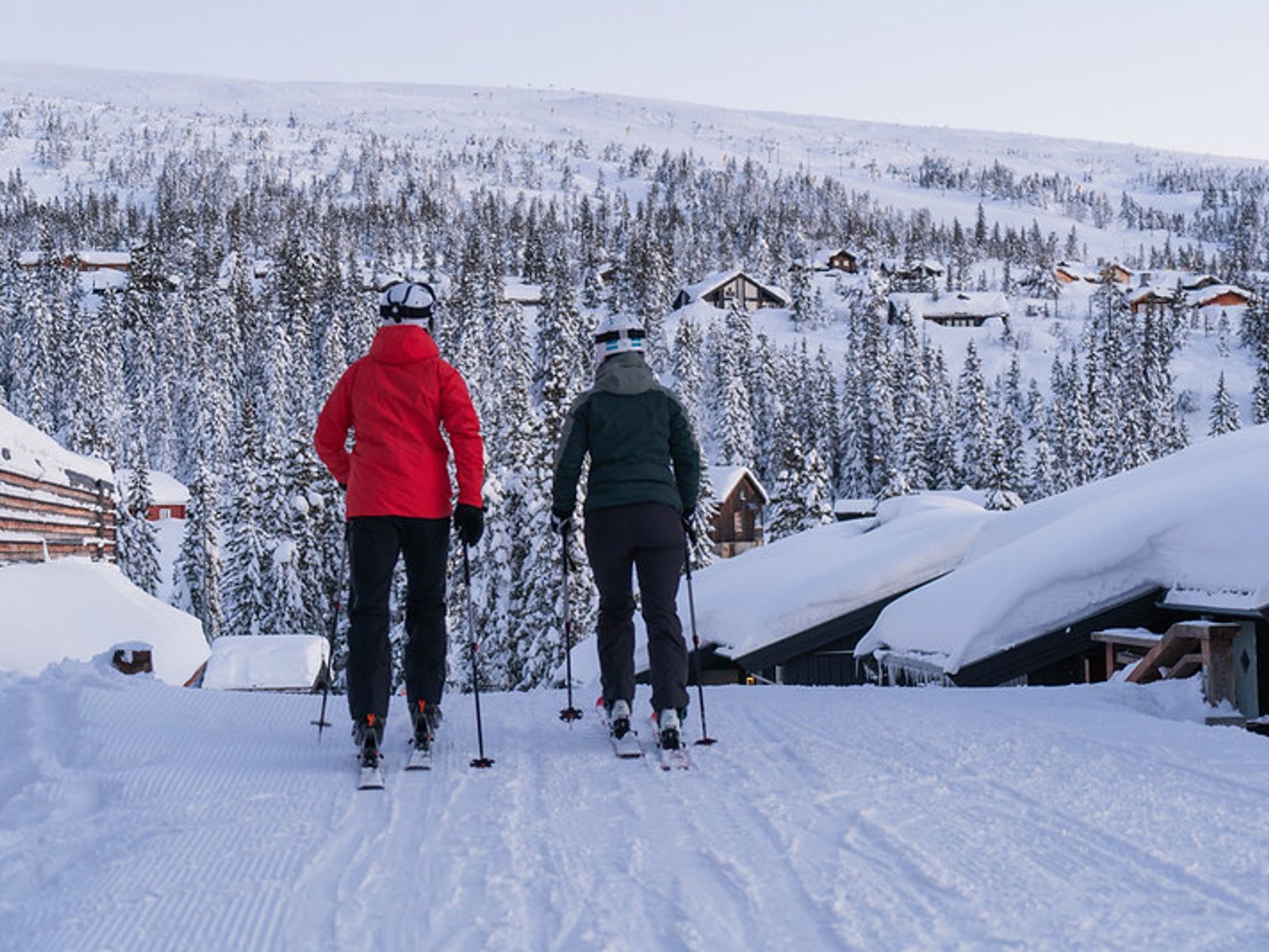 to personer står på ski nedover en snødekt bakke.